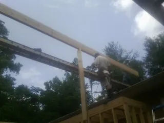 Carpenter setting a ridge beam over a new addition frame — Ice Dam Removal by Roofing Brothers in Renfrew