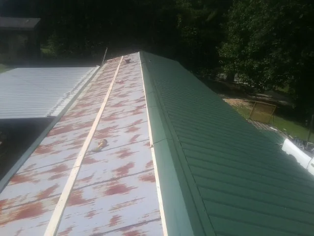 Old rusted panels beside newly installed green metal roofing — Wind Damage Roof Repair by Roofing Brothers in Renfrew