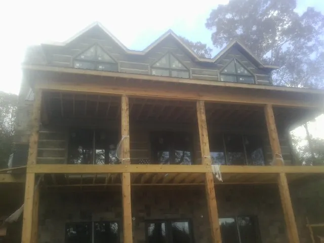 Dormers and porch framing on a large log home under construction — Roof Coating work by our crew in Renfrew