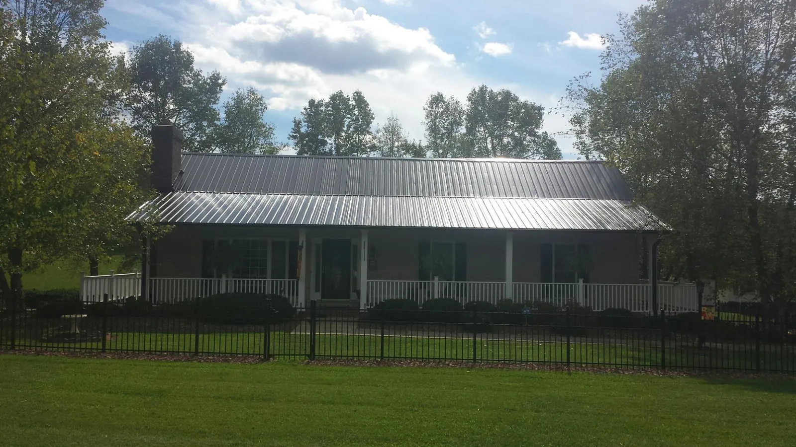 Gray metal roof on a brick ranch with a full width front porch — Gutter Guard Installation work by our crew in Renfrew