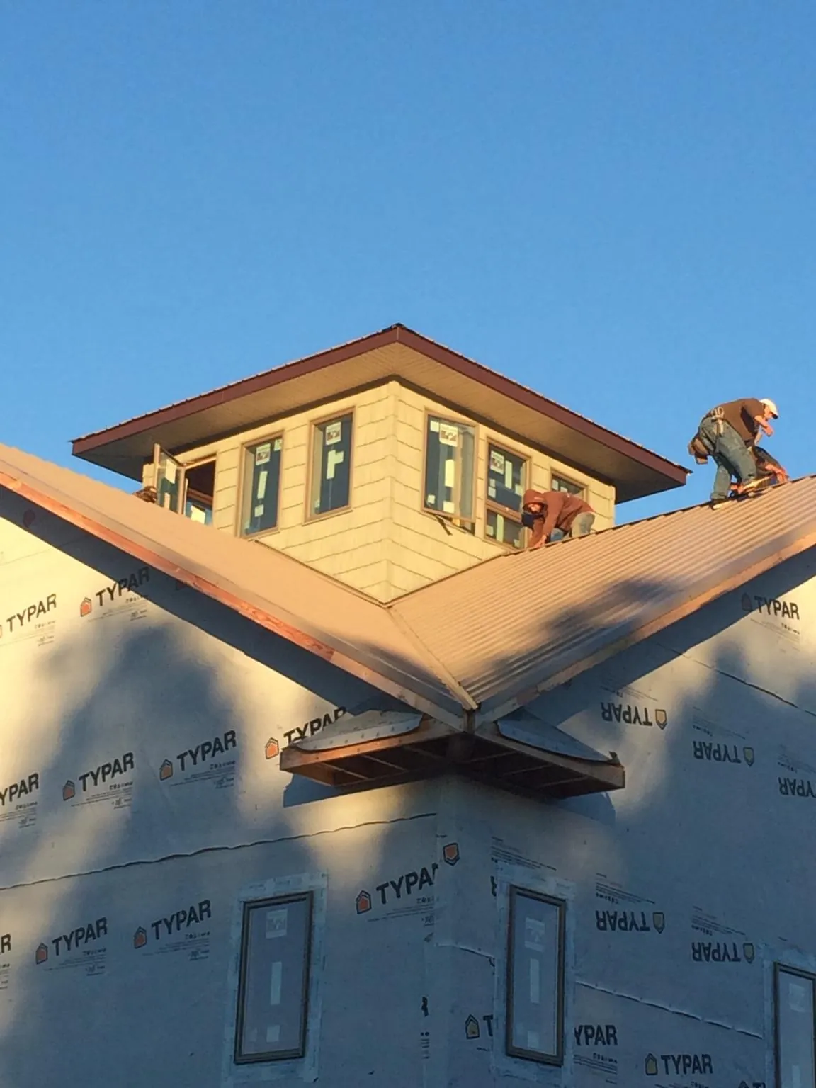 Roofers working around a rooftop cupola on a new metal roof at sunset — Roof Waterproofing in Renfrew by Roofing Brothers